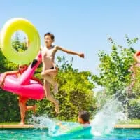 Kid jumping in pool with pool toys